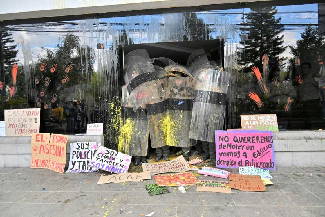 Officers in riot gear stand guard as a group of women protest in front of Ecuador's police headquarters Officers in riot gear stand guard as a group of women protest in front of Ecuador's police headquarters