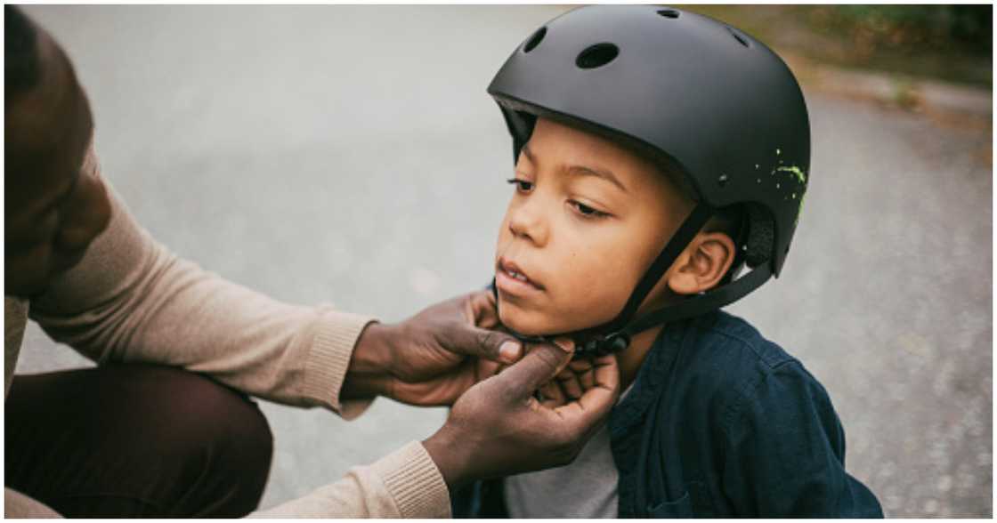 A parent buckles up the helmet of his child A parent buckles up the helmet of his child