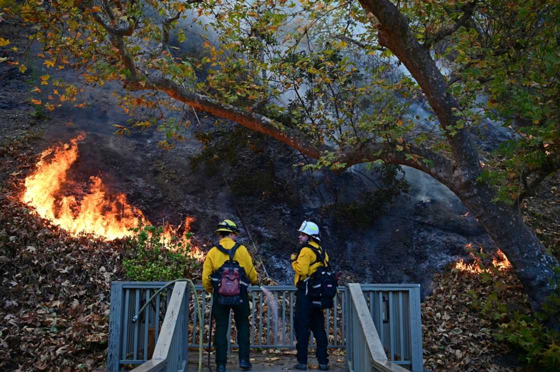Firefighters work to put out flames behind a home in the Mandeville Canyon neighborhood of Los Angeles Firefighters work to put out flames behind a home in the Mandeville Canyon neighborhood of Los Angeles