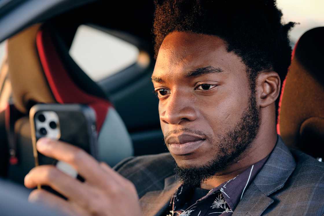 A man using his phone while sitting inside a car