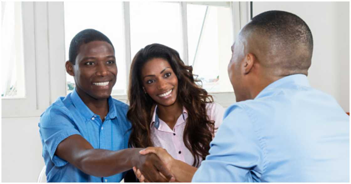 A couple is all smiles as they shake hands with a landlord