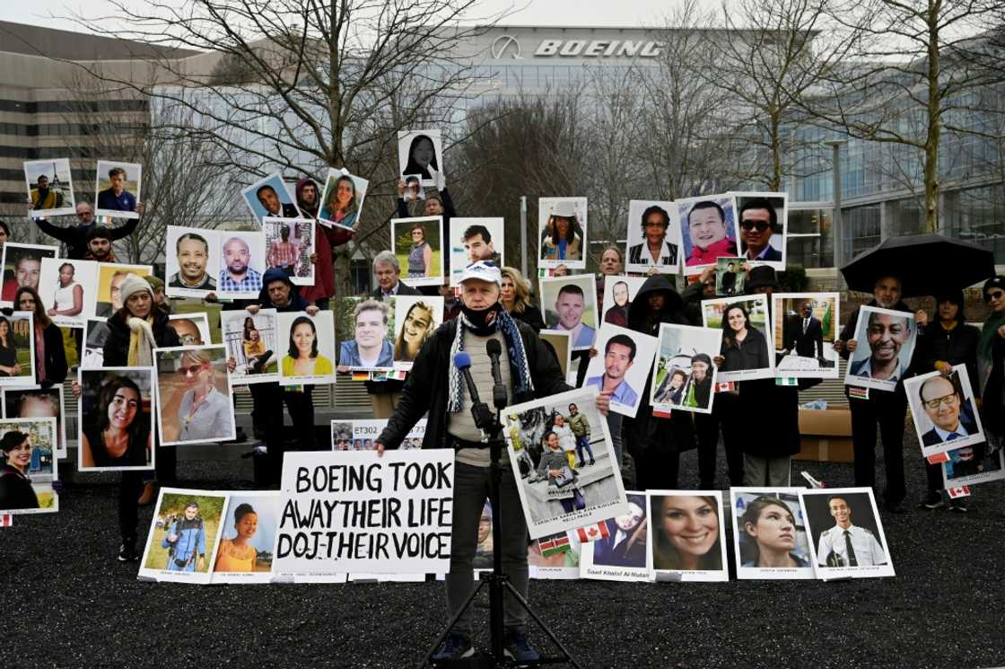 A man stands before photographs of victims of the Boeing 737 MAX crash in Ethiopia in March 2019, at a protest outside the US aircraft manufacturer's office in Arlington, Virginia