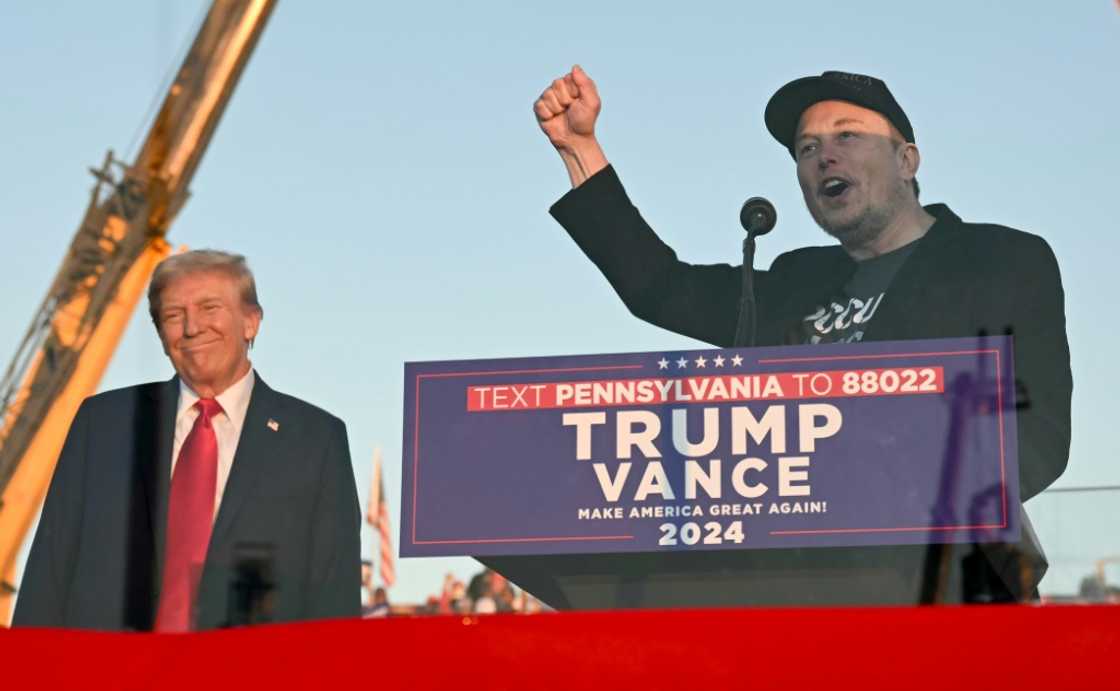 Tesla CEO Elon Musk (R) speaks on stage as he joins former US President and Republican presidential candidate Donald Trump during a campaign rally