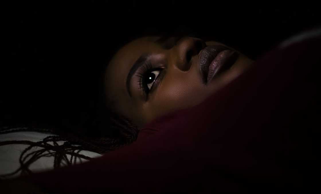 A woman lies awake in bed, staring into the darkness.