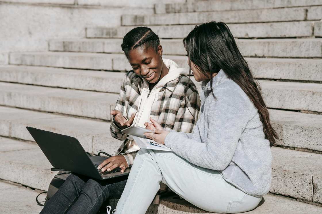 Two college girls having a discussion at the stairs Two college girls having a discussion at the stairs