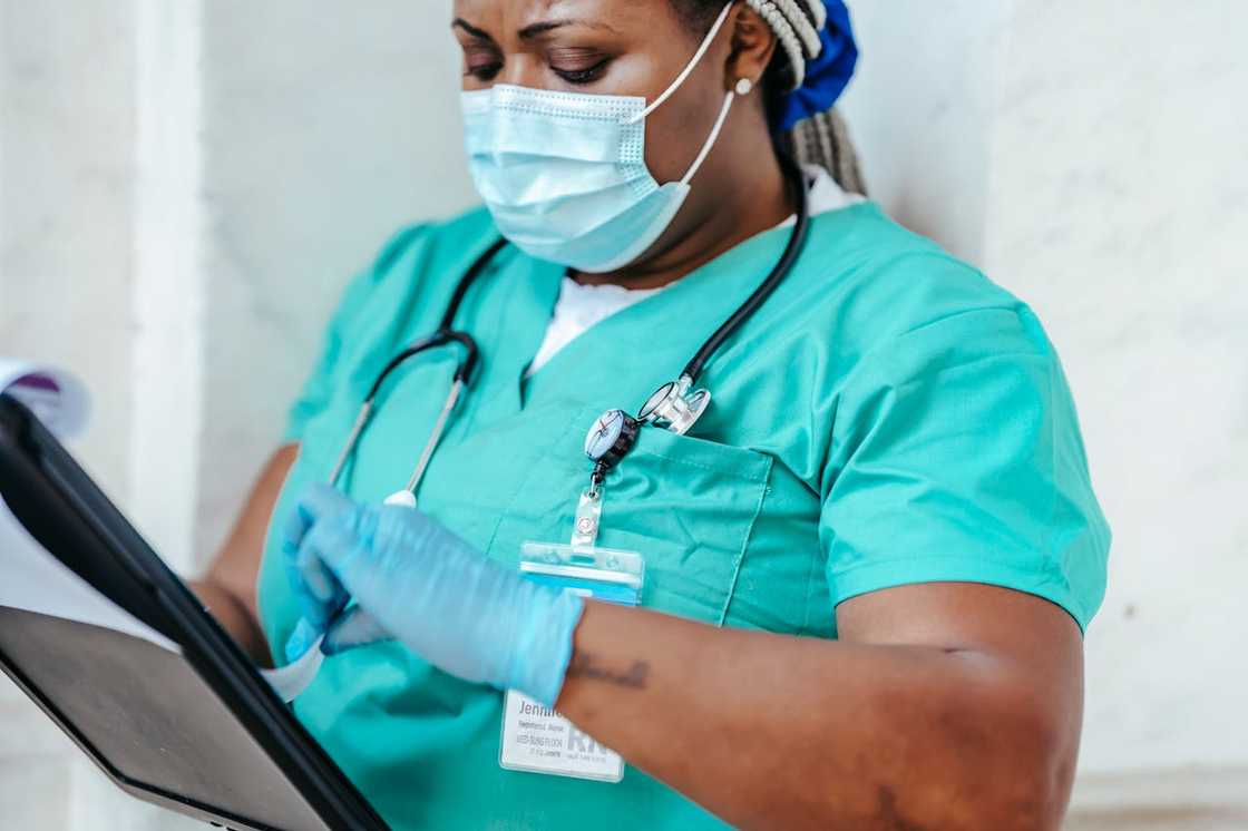 A nurse in scrubs reviewing medical notes.