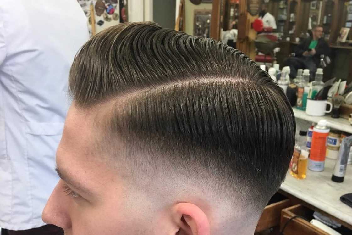A man with a pompadour haircut is inside a barber shop A man with a pompadour haircut is inside a barber shop