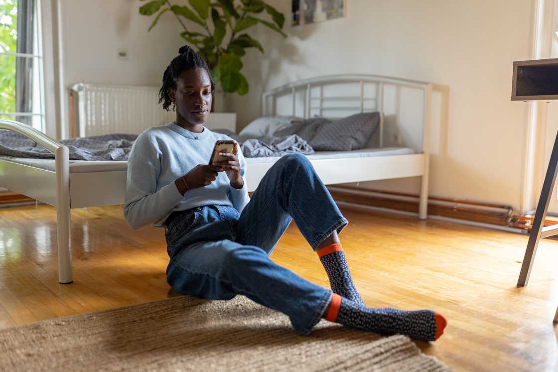 A lady is using her phone in the bedroom A lady is using her phone in the bedroom