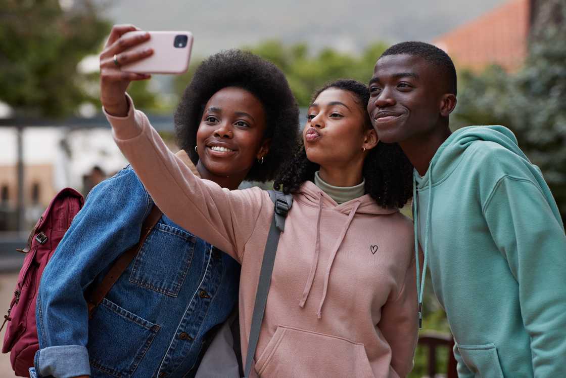 Teenage girl puckering while taking selfie with friends