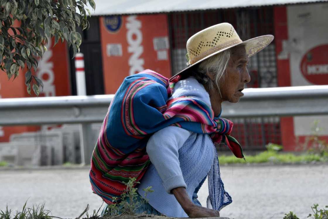 An elderly woman walks along a road that links Cochabamba with La Paz, where barricades have been erected by supporters of former Bolivian president Evo Morales