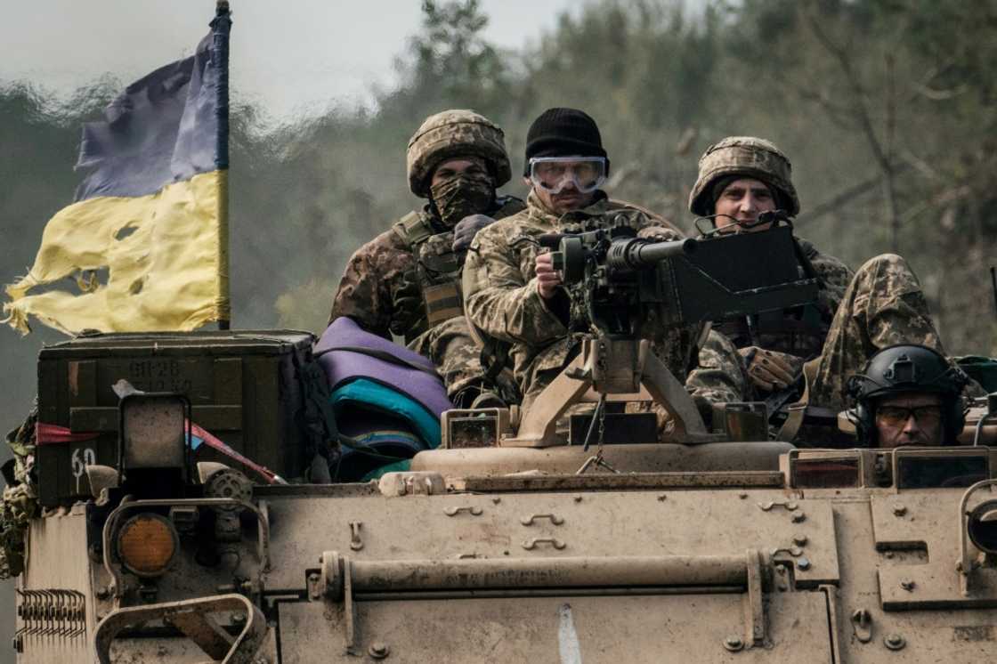 Ukrainian soldiers ride on an armoured vehicle near the recently retaken town of Lyman in Donetsk region