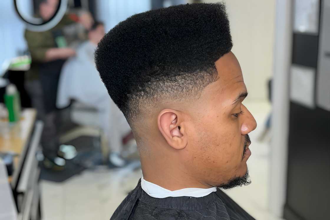 A man is rocking a high top hairstyle with a fade