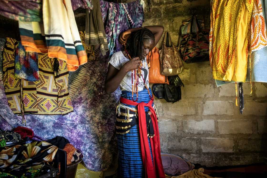 A young woman named Vicko prepares her outfit ahead of the ceremony to mark the end of the men's initiation period A young woman named Vicko prepares her outfit ahead of the ceremony to mark the end of the men's initiation period