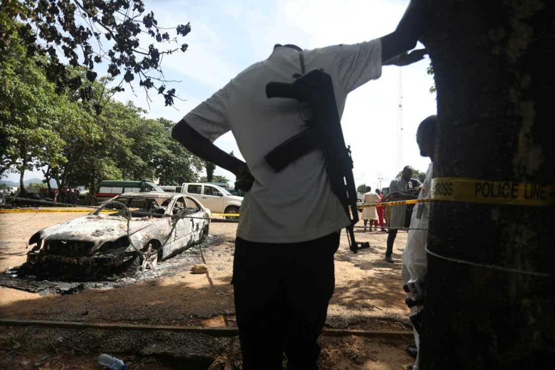 A police officer stands beside a burnt prison vehicle in Abuja, Nigeria on July 6, 2022 after suspected Boko Haram gunmen attacked the Kuje Medium prison A police officer stands beside a burnt prison vehicle in Abuja, Nigeria on July 6, 2022 after suspected Boko Haram gunmen attacked the Kuje Medium prison
