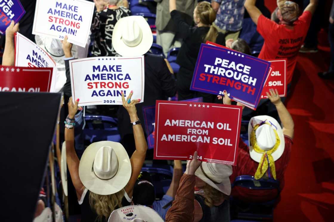 People hold signs that read "American Oil from American Soil" at a Trump rally People hold signs that read "American Oil from American Soil" at a Trump rally