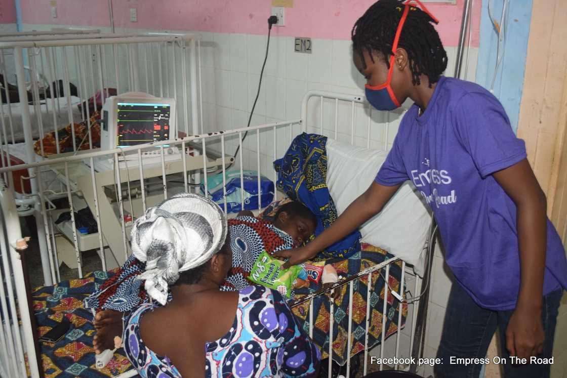 Photo of Empress Esi giving snacks to children at a hospital.