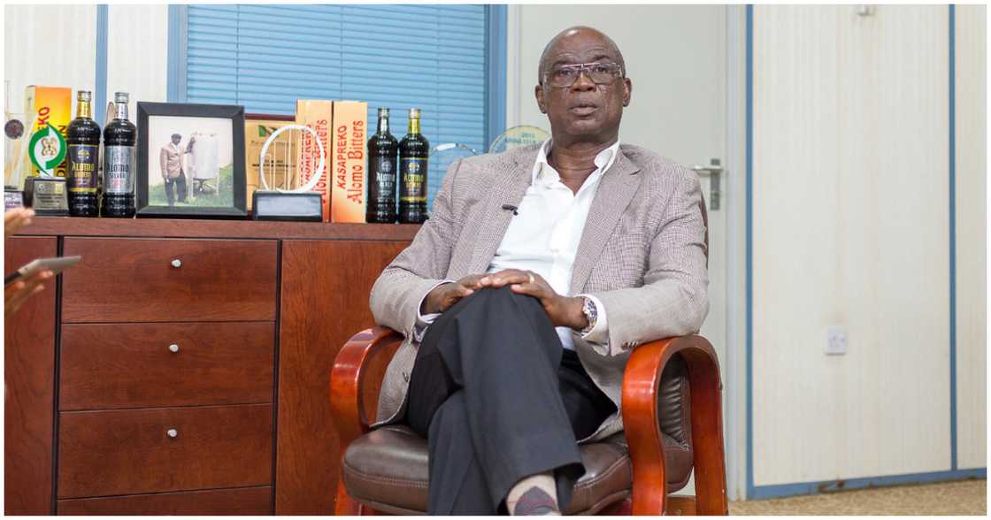 Dr Kwabena Adjei poses in front of an array of his alcoholic beverages