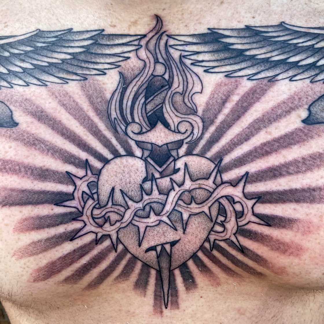 A black and white chest Angel wings and sacred heart tattoo