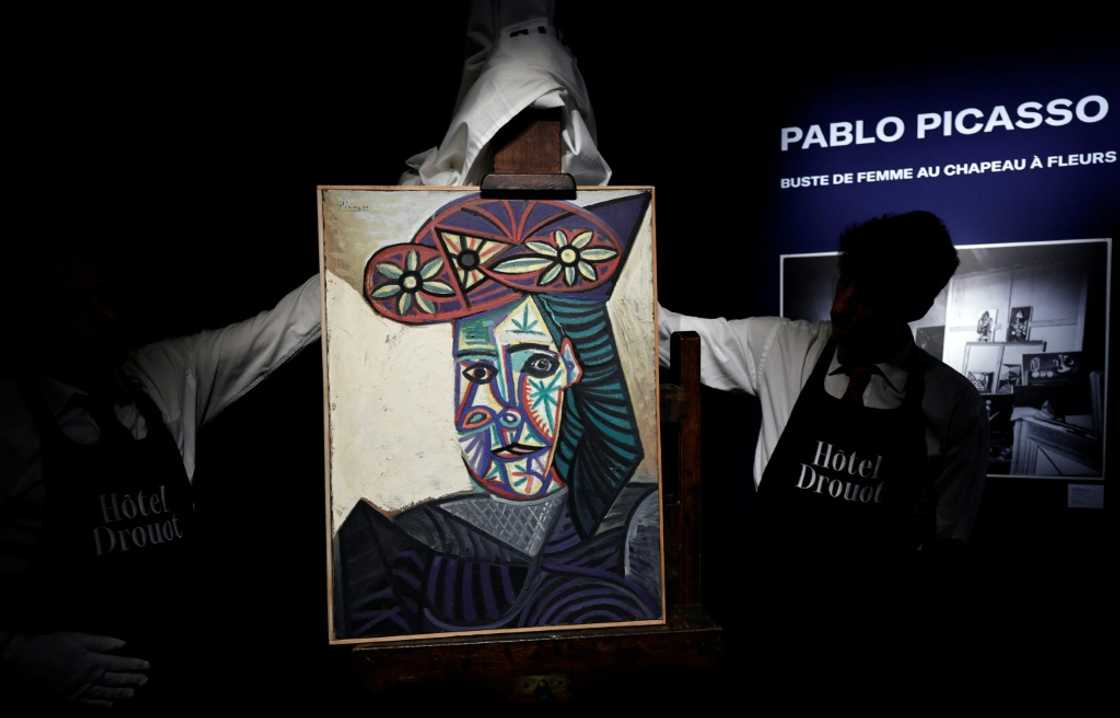 Employees unveil a painting by French artist Pablo Picasso titled 'Bust of a Woman With a Flowery Hat' ahead of an auction in Paris Employees unveil a painting by French artist Pablo Picasso titled 'Bust of a Woman With a Flowery Hat' ahead of an auction in Paris
