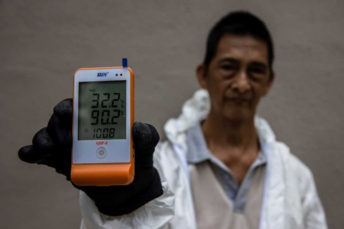 Pest control worker Wah shows the temperature recorded inside the protective full-body suit his job requires Pest control worker Wah shows the temperature recorded inside the protective full-body suit his job requires