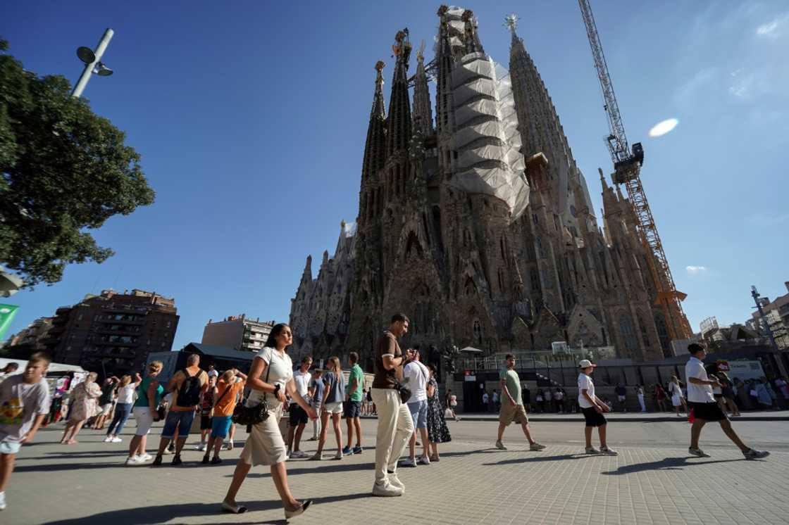 Tourists walk past the Sagrada Familia basilica in Barcelona on August 2, 2025