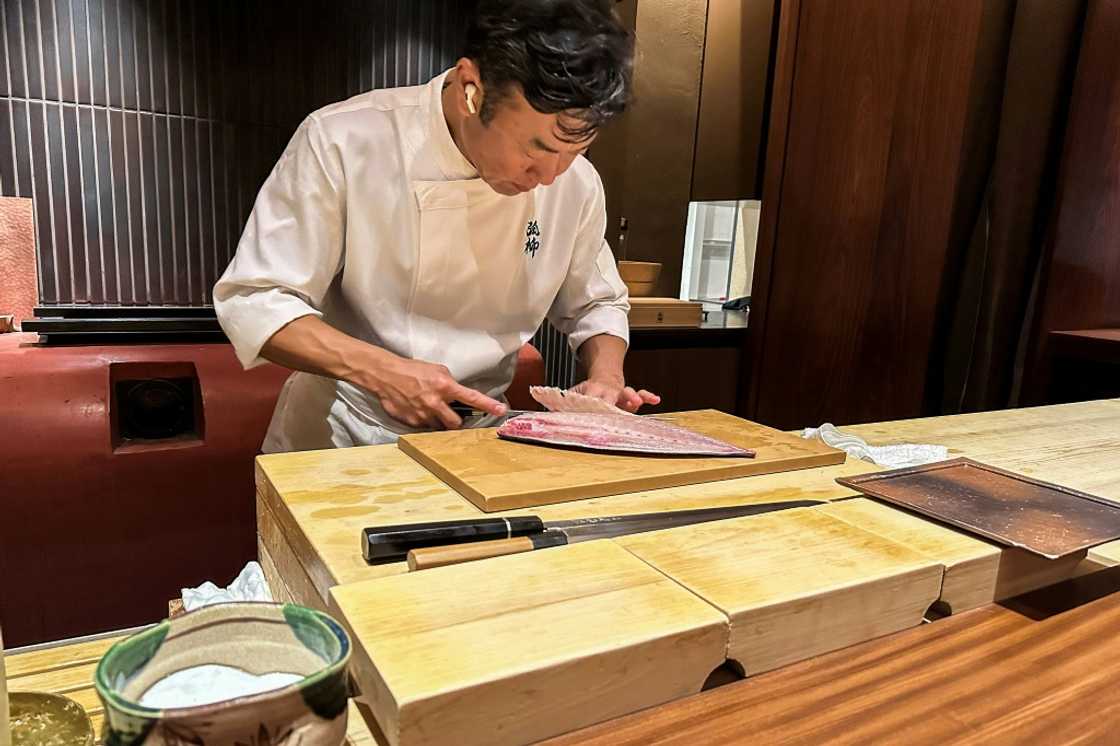 Chef Shintaro Matsuo expertly slices through a piece of yellowtail with a knife made in the nearby city of Sakai, at his restaurant in Osaka