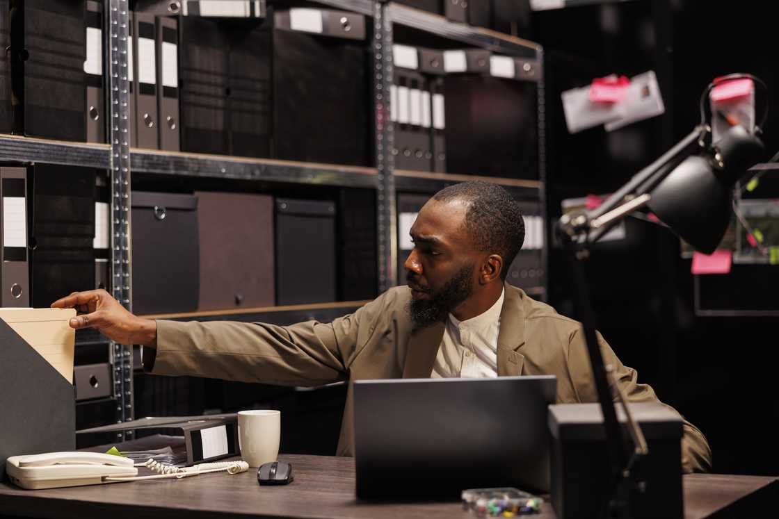 A hidden camera records as a man reaches for a folder in an office. A hidden camera records as a man reaches for a folder in an office.
