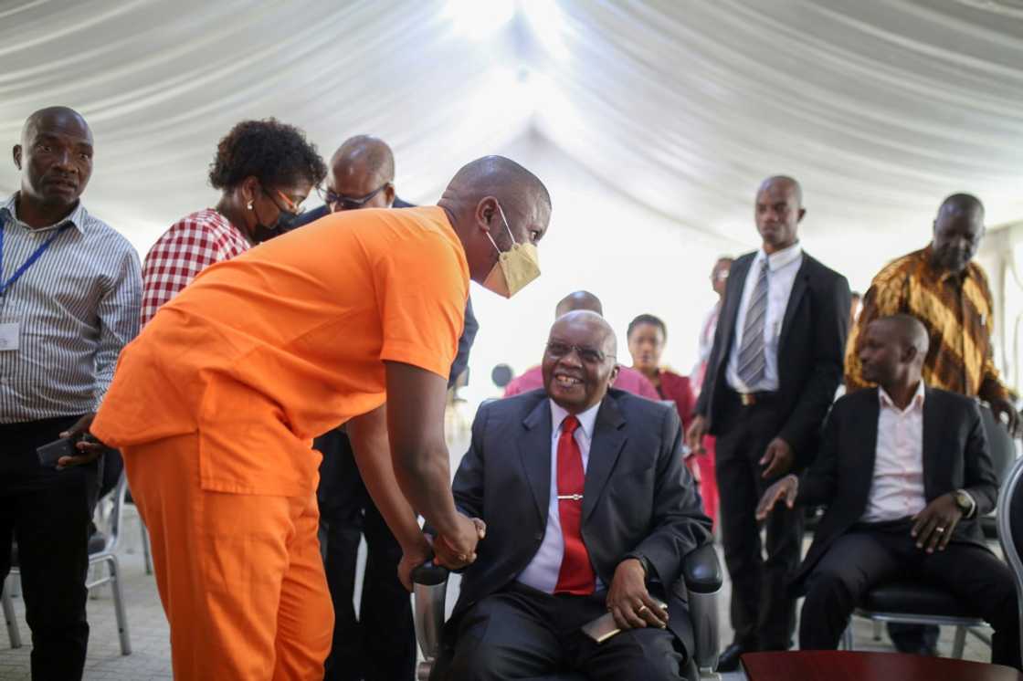 Former president Armando Guebuza, seated, greets his son Ndambi, a defendant in the corruption trial Former president Armando Guebuza, seated, greets his son Ndambi, a defendant in the corruption trial