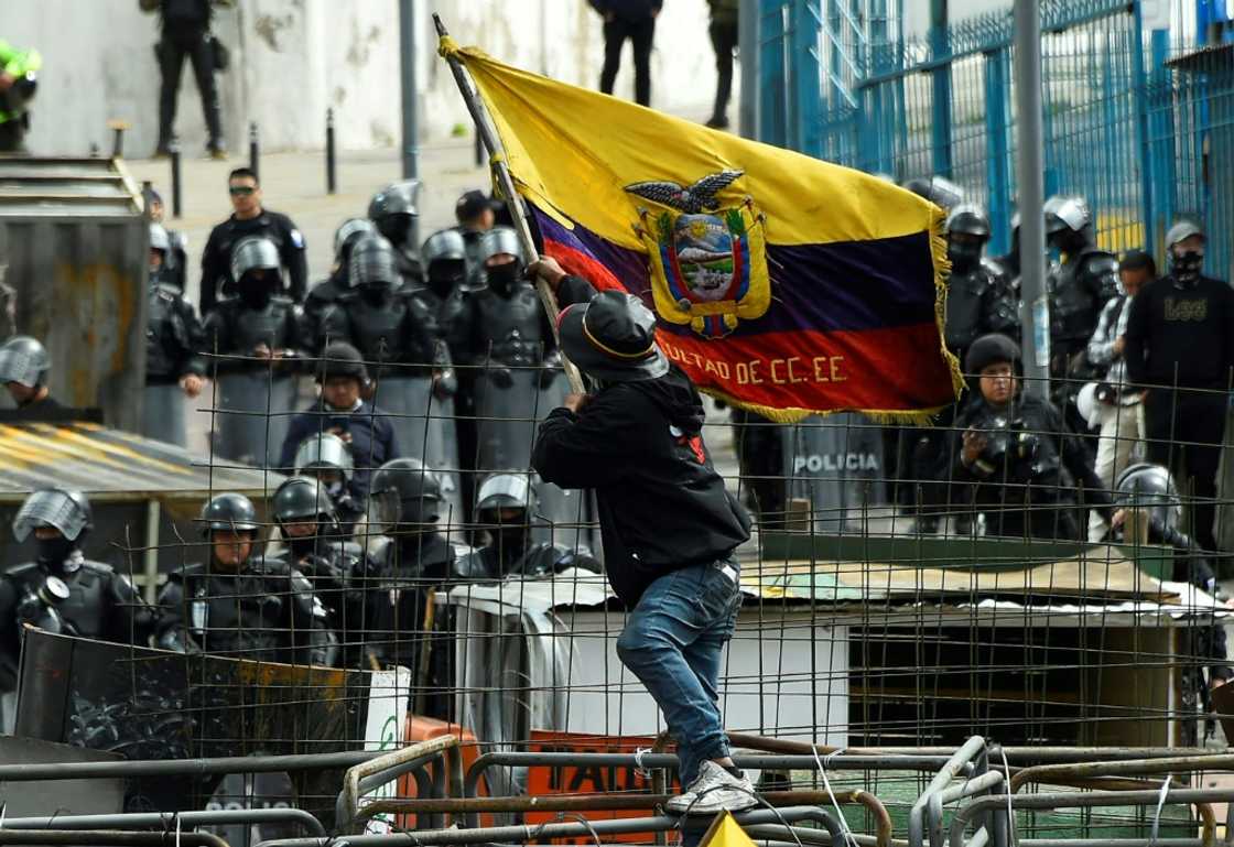 A demonstrator faces off with police officers near the National Assembly in Quito on June 25, 2022
