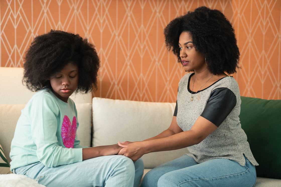 Sad daughter talks to her mother on the sofa in the living room Sad daughter talks to her mother on the sofa in the living room