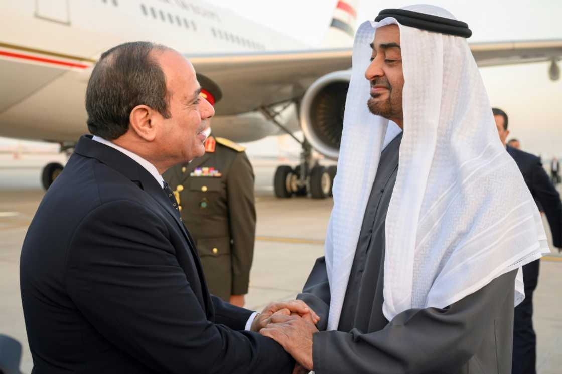 A handout picture released by the United Arab Emirates' presidential court shows Emirati President Sheikh Mohamed bin Zayed Al-Nahyan (R) welcoming Egypt's President Abdel Fattah al-Sisi in Abu Dhabi on February 12, 2023