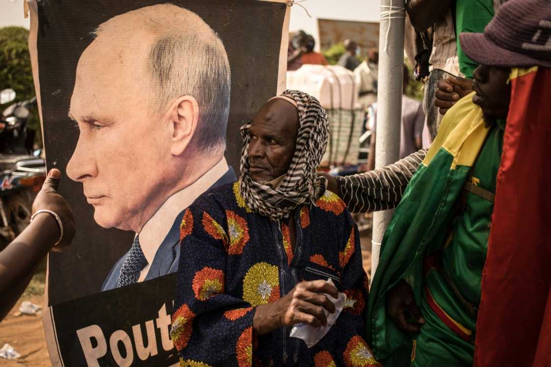 New best friend: a Malian man sits in front of a portrait of Russian President Vladimir Putin New best friend: a Malian man sits in front of a portrait of Russian President Vladimir Putin