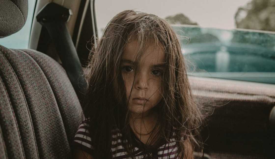 A young child sitting quietly in the back seat of a car. A young child sitting quietly in the back seat of a car.