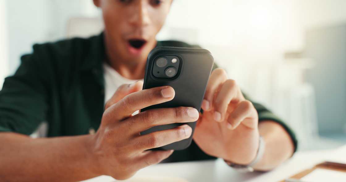 Person reacts with surprise while looking at a smartphone. Person reacts with surprise while looking at a smartphone.