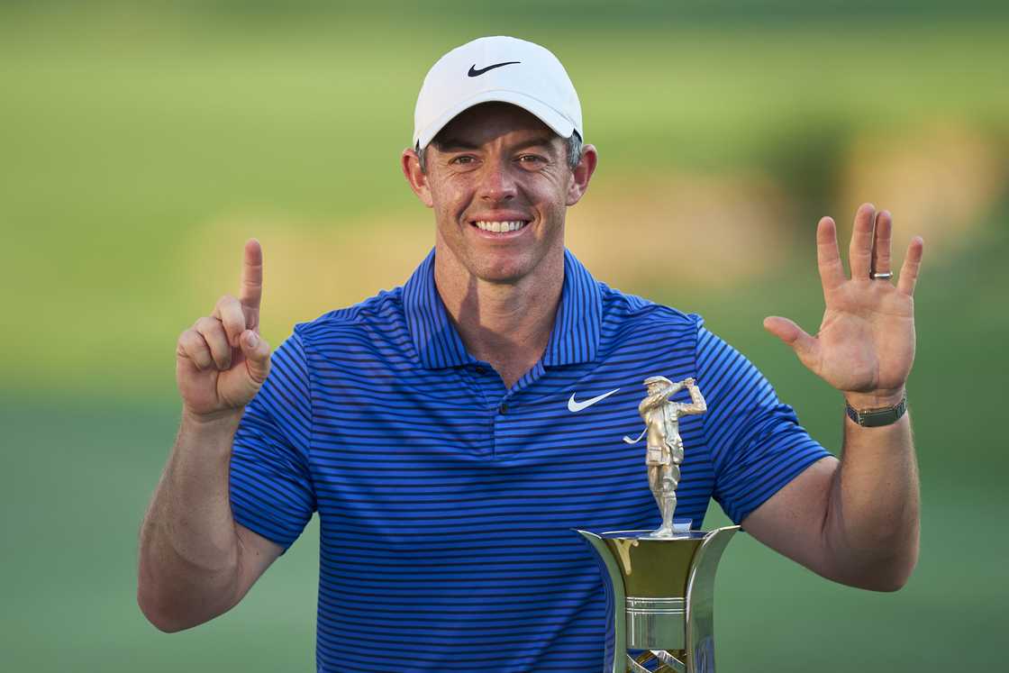 Rory McIlroy poses with the Race to Dubai trophy on the 18th green whilst gesturing 'six' Rory McIlroy poses with the Race to Dubai trophy on the 18th green whilst gesturing 'six'