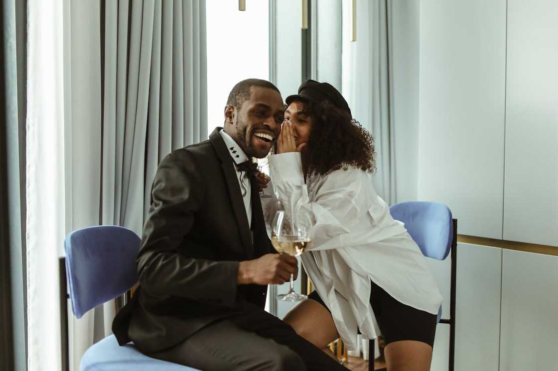 A woman whispers in the ear of a man.