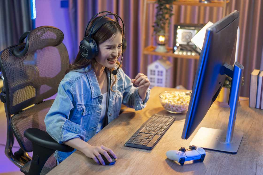 A woman playing a computer game on a laptop at night