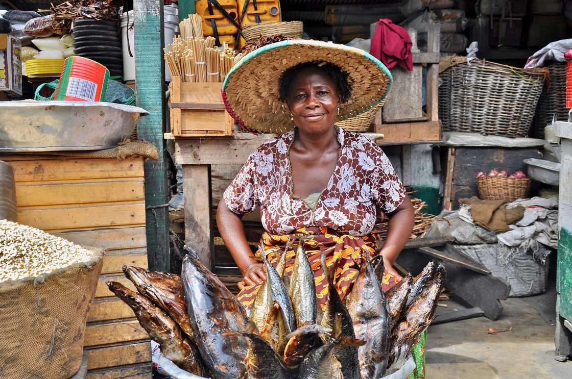 A woman selling smoked fish in the market A woman selling smoked fish in the market