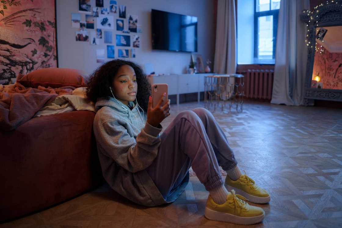 A young girl scrolls through her smartphone in the bedroom. A young girl scrolls through her smartphone in the bedroom.