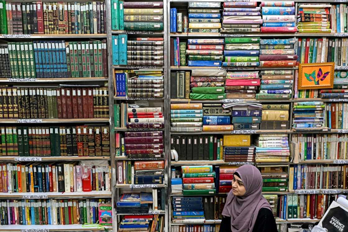 A student sits under crowded shelves at the Hazrat Shah Waliullah Public Library.