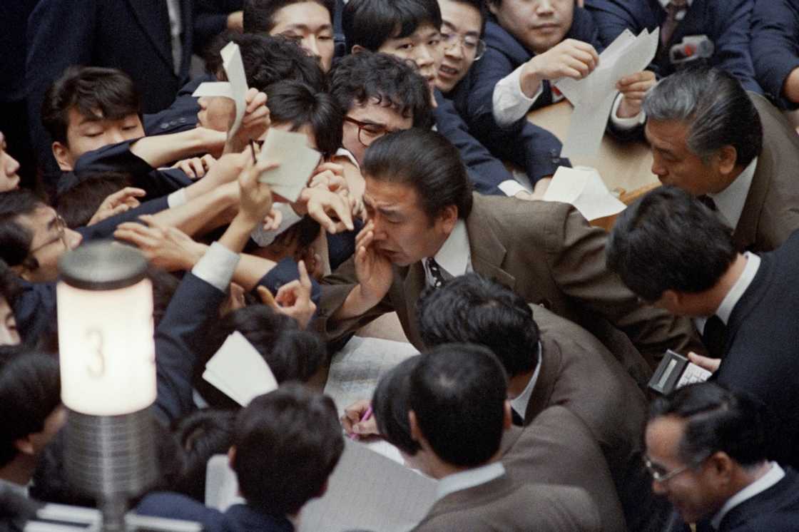 Floor traders jostle on January 7, 1988 as stock prices soar on the Tokyo Stock Exchange following the sharp rise in the yen against the dollar Floor traders jostle on January 7, 1988 as stock prices soar on the Tokyo Stock Exchange following the sharp rise in the yen against the dollar