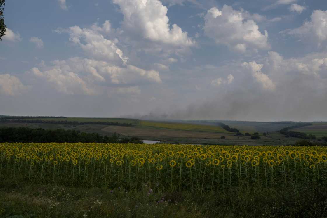 A smoke plume billows on the horizon behind sunflower fields, in eastern Ukraine on August 11, 2022 A smoke plume billows on the horizon behind sunflower fields, in eastern Ukraine on August 11, 2022