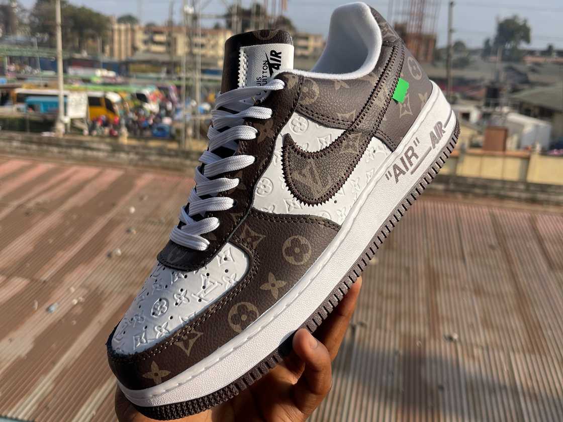 A hand is holding a Louis Vuitton x Nike Air Force One