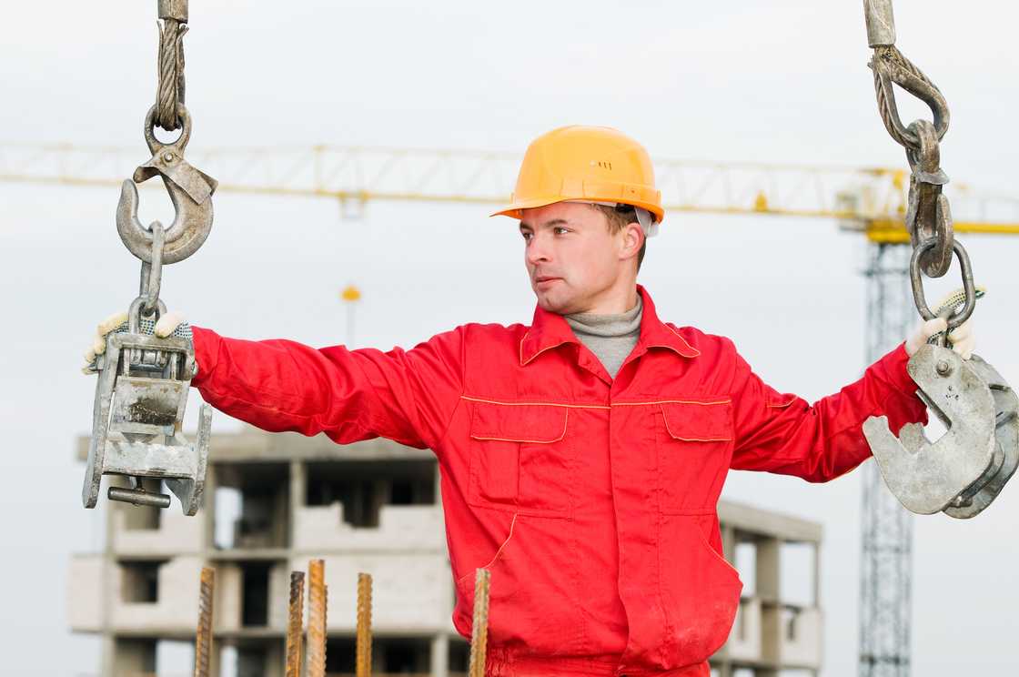 A rigger builder on site holds a crane with straps. A rigger builder on site holds a crane with straps.