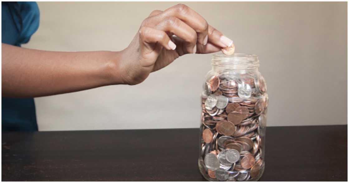 A woman saves money in a jar