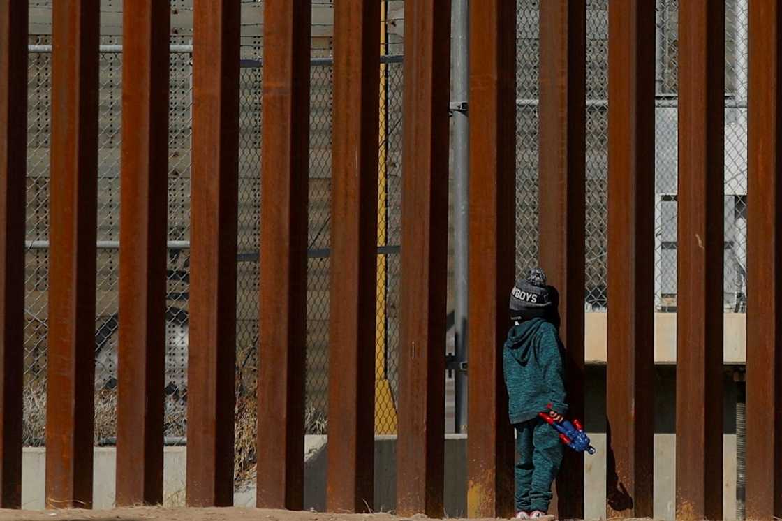 A Venezuelan child migrant stands by the wall along the Mexican-US border A Venezuelan child migrant stands by the wall along the Mexican-US border