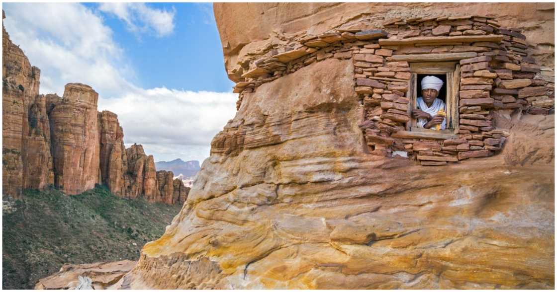 A priest stares out the window of the church A priest stares out the window of the church