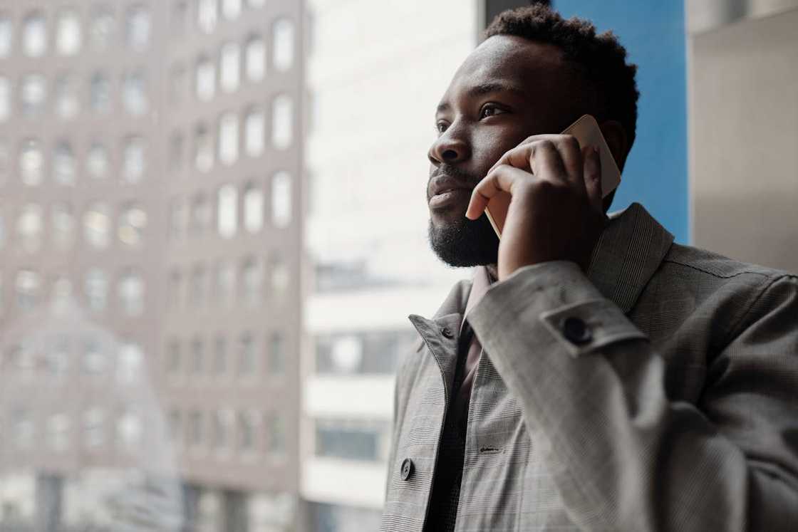 A man looks out a window while talking on his phone.