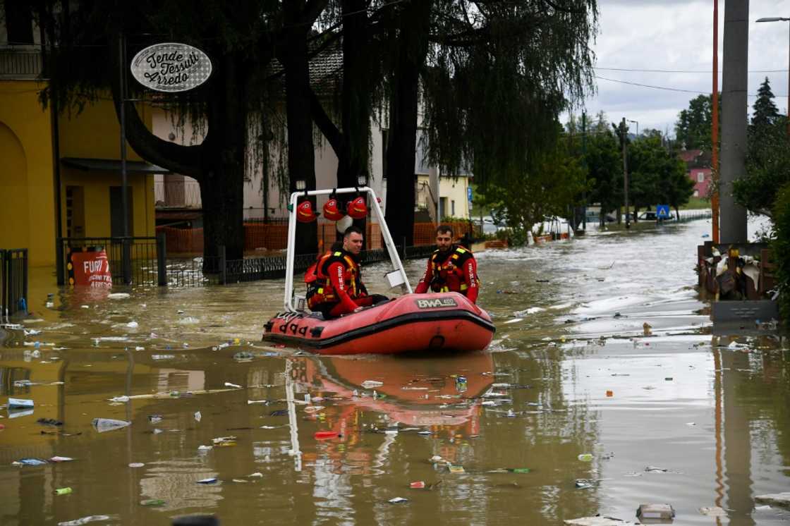 Volunteer firefighters ride their dinghy across a street flooded by the river Savio in the Ponte Vecchio district of Cesena, central eastern Italy, on May 17, 2023 Volunteer firefighters ride their dinghy across a street flooded by the river Savio in the Ponte Vecchio district of Cesena, central eastern Italy, on May 17, 2023