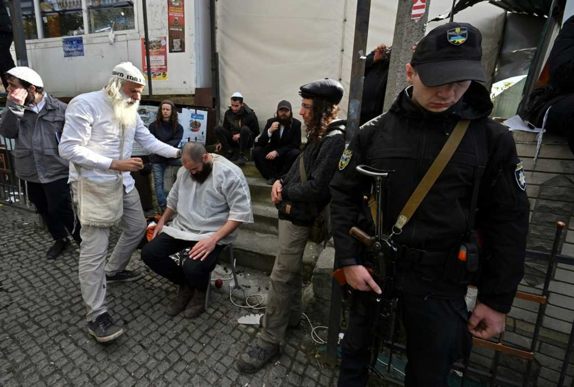 An armed policeman stands guard as Hasidic Jewish pilgrims have their hair cut after praying at the tomb of Rabbi Nachman to mark the Jewish new year An armed policeman stands guard as Hasidic Jewish pilgrims have their hair cut after praying at the tomb of Rabbi Nachman to mark the Jewish new year